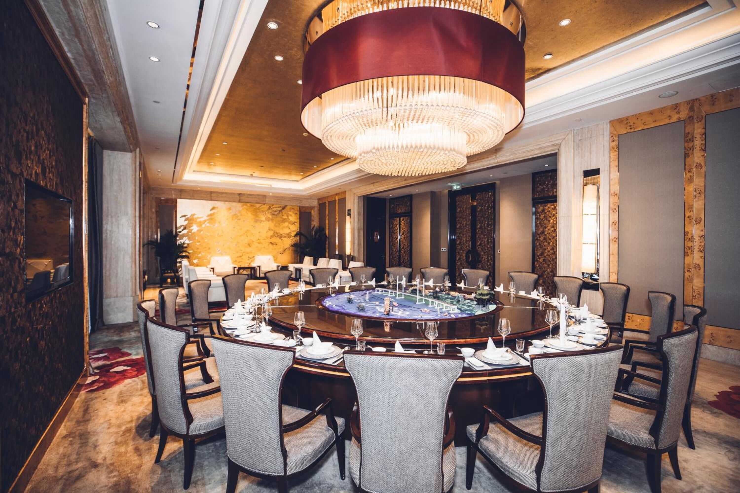 A conference room with a round table, chairs, and a chandelier.