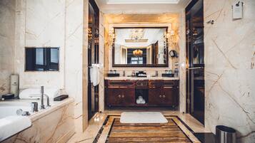 Un bagno lussuoso con pavimento in marmo, un grande specchio, una vasca da bagno e un mobile lavabo con lavandino e porta asciugamani.