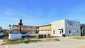 A motel with a modern design, featuring a parking lot and a clear sky.