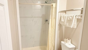 A bathroom with a shower, toilet, and a towel rack.