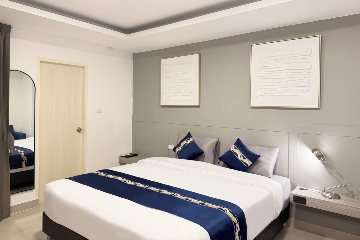 Ein modernes Hotelzimmer mit einem großen Bett, einem Nachttisch mit Lampe und zwei gerahmten Kunstwerken an der Wand.