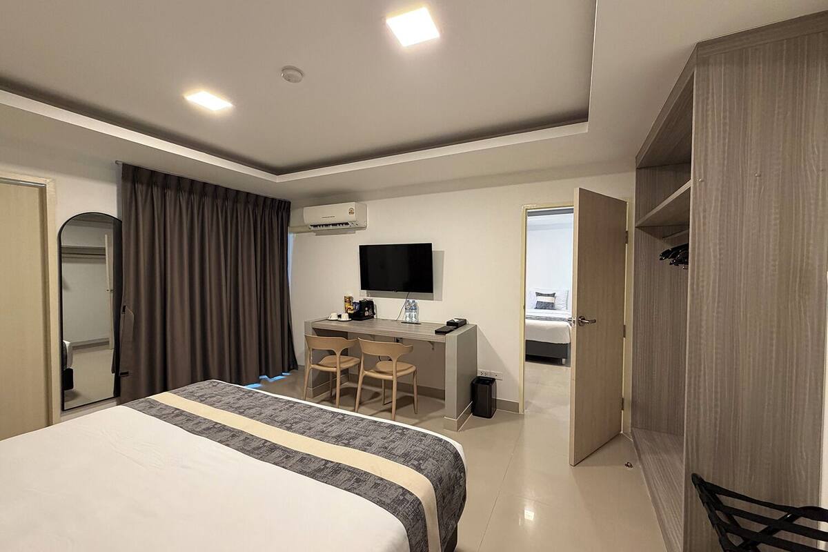 Een hotelkamer met een bed, een bureau met stoel, een televisie en een kledingkast.