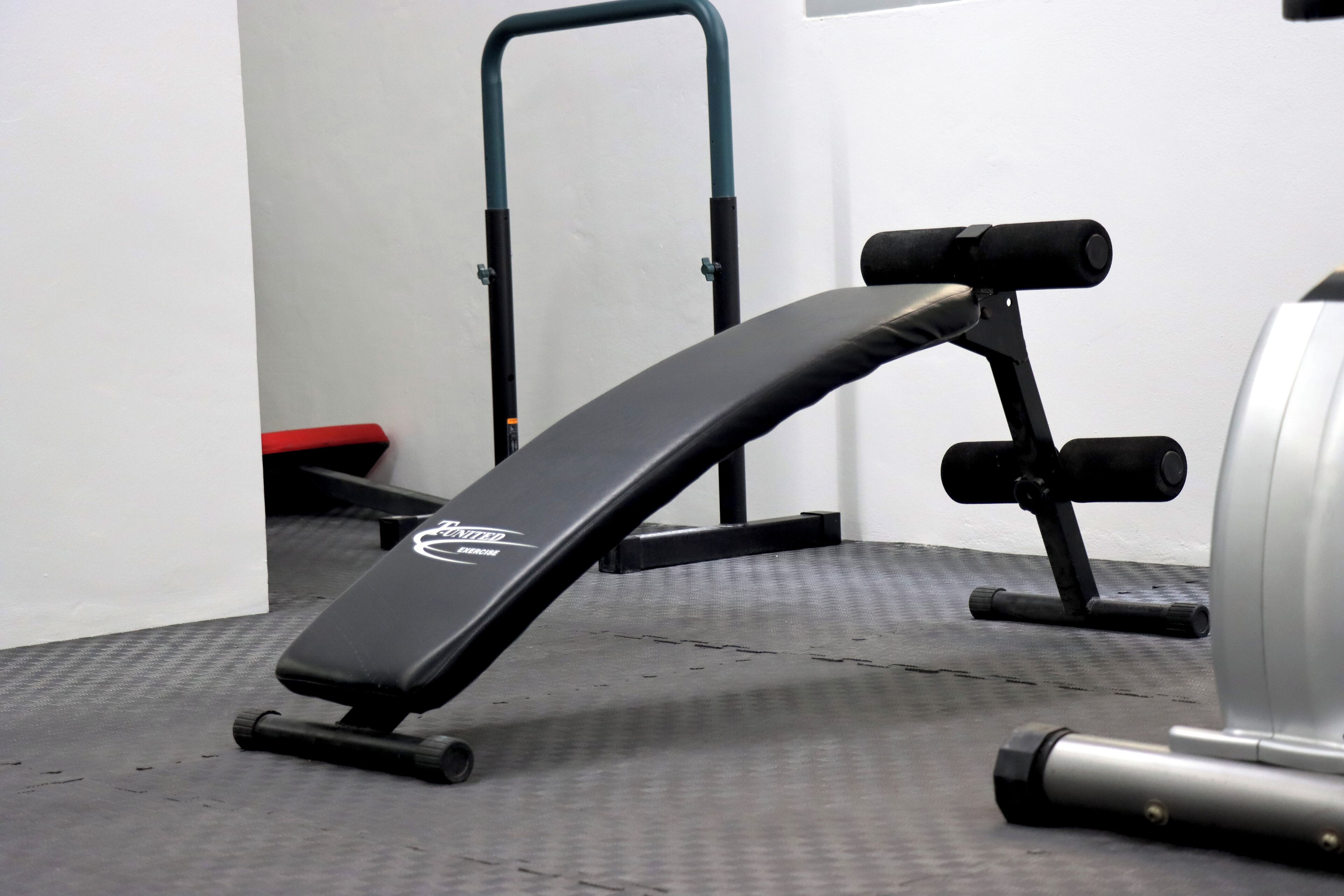 Un gimnasio con una banca, una barra de dominadas y una máquina de pesas.