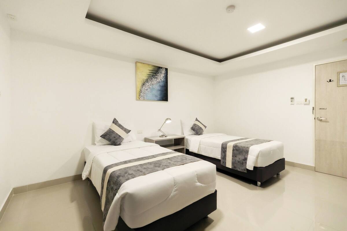 Een hotelkamer met twee bedden, een nachtkastje, een bureau en een deur.