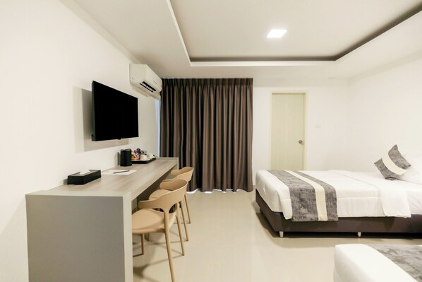 Una habitación de hotel moderna con cama, escritorio con sillas, televisor de pantalla plana y aire acondicionado.