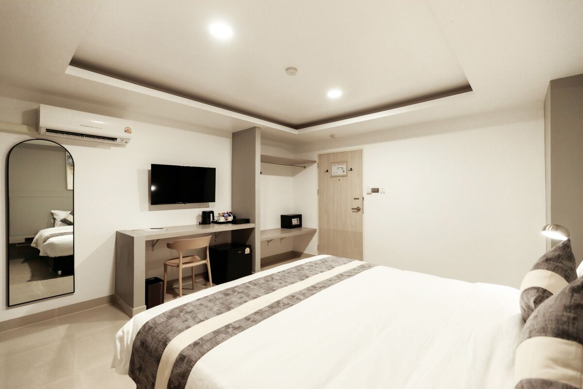 Une chambre d’hôtel moderne équipée d’un lit, d’un bureau, d’une chaise et d’un téléviseur.