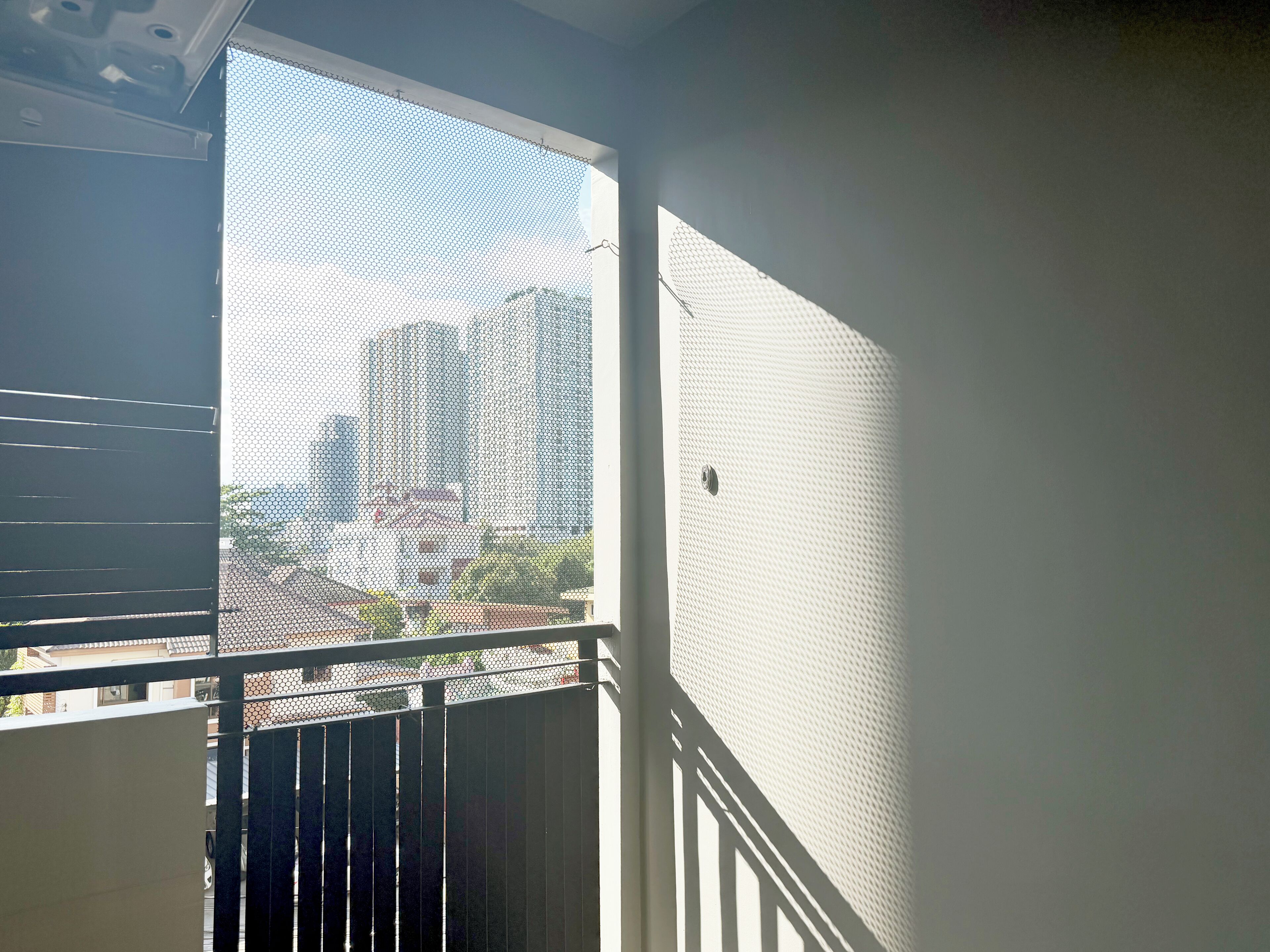 A balcony with a metal railing and a mesh screen.