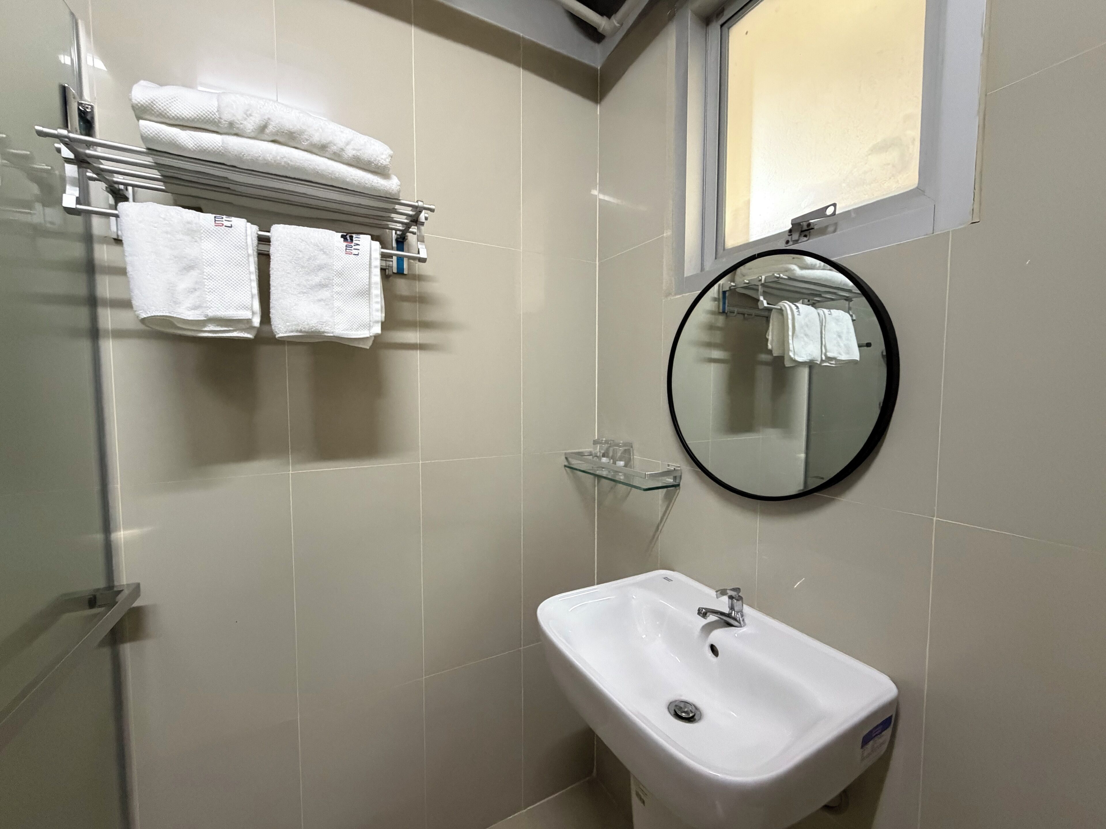A bathroom with a sink, mirror, towel rack, and a window.