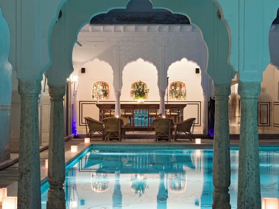 A pool area with a bar and seating, surrounded by arches and columns.