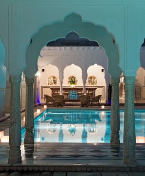 A pool area with a bar and seating, surrounded by arches and columns. - Samode Bagh (Chomu)