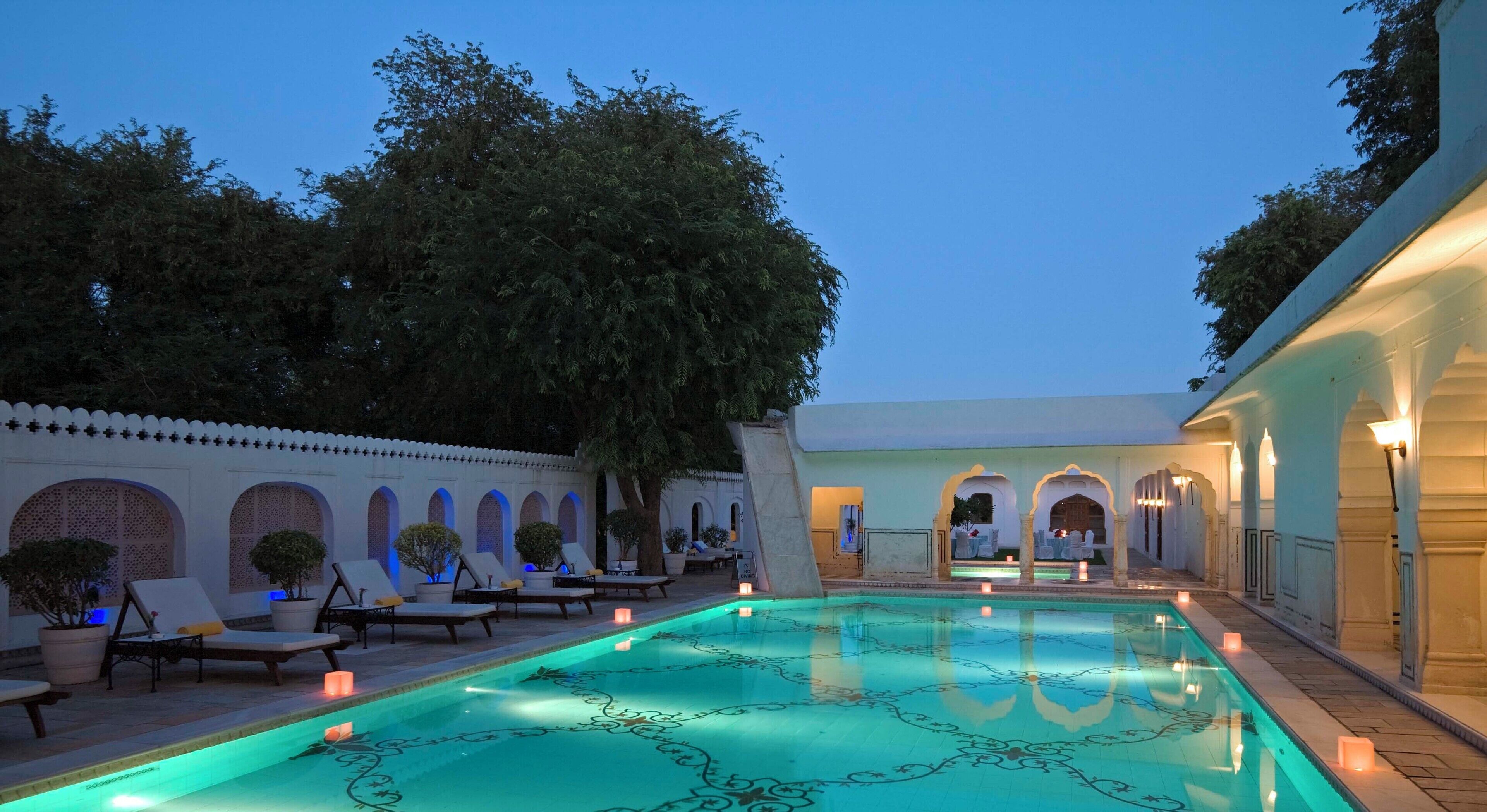 A pool area with lounge chairs and a fountain.