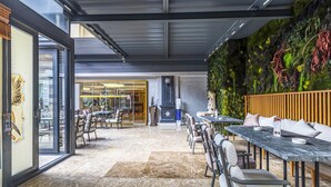 A modern indoor dining area with marble flooring, a long table with chairs, and a green wall with plants. - Euro Stars Hotel Old City (Istanbul)