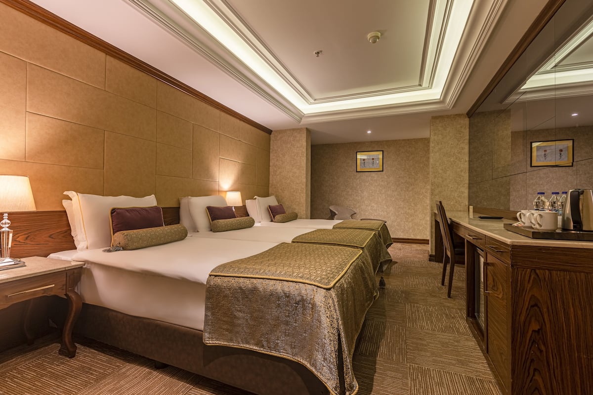 A hotel room with a large bed, bedside tables, a desk, and a mirror.