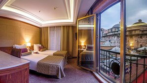 A hotel room with two beds, a desk, and a balcony with a view of a historic building. - Euro Stars Hotel Old City (Istanbul)
