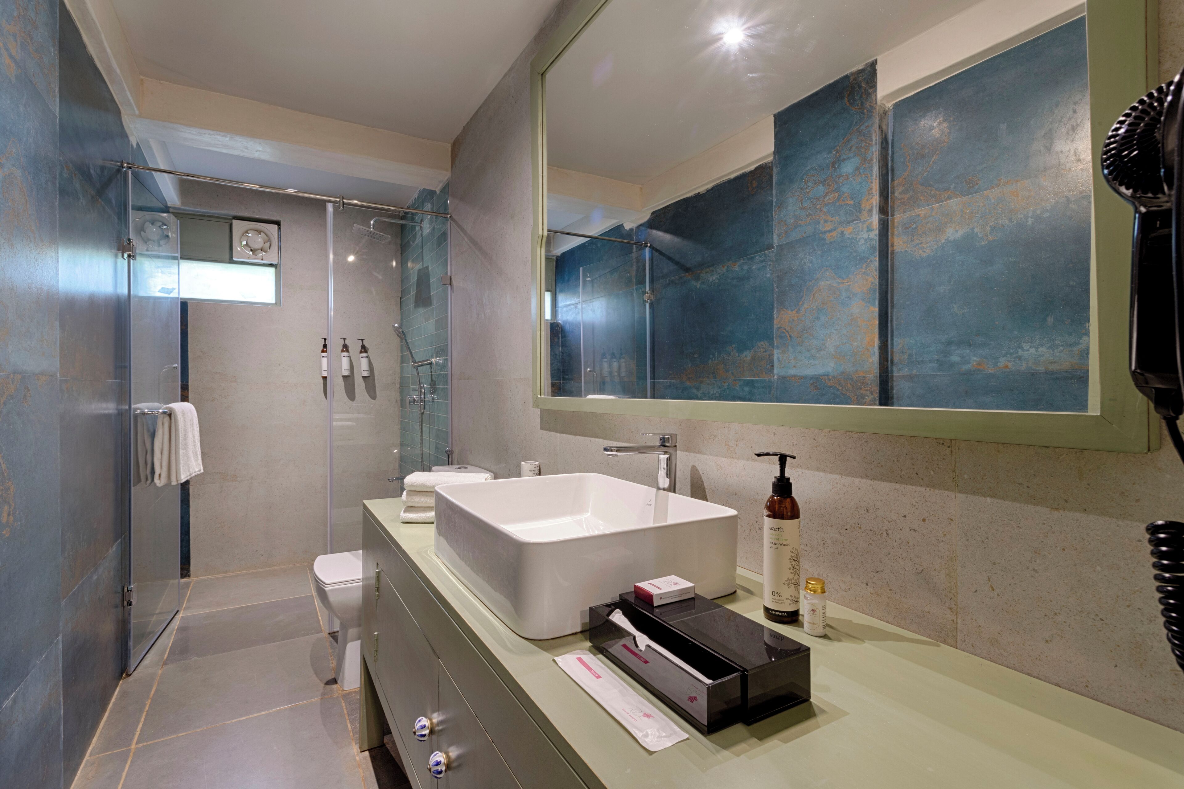 A modern bathroom with a large sink, a glass shower enclosure, and a large mirror.
