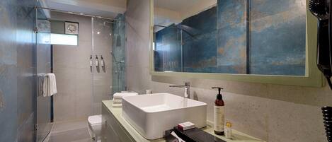 A modern bathroom with a large sink, a glass shower enclosure, and a large mirror.