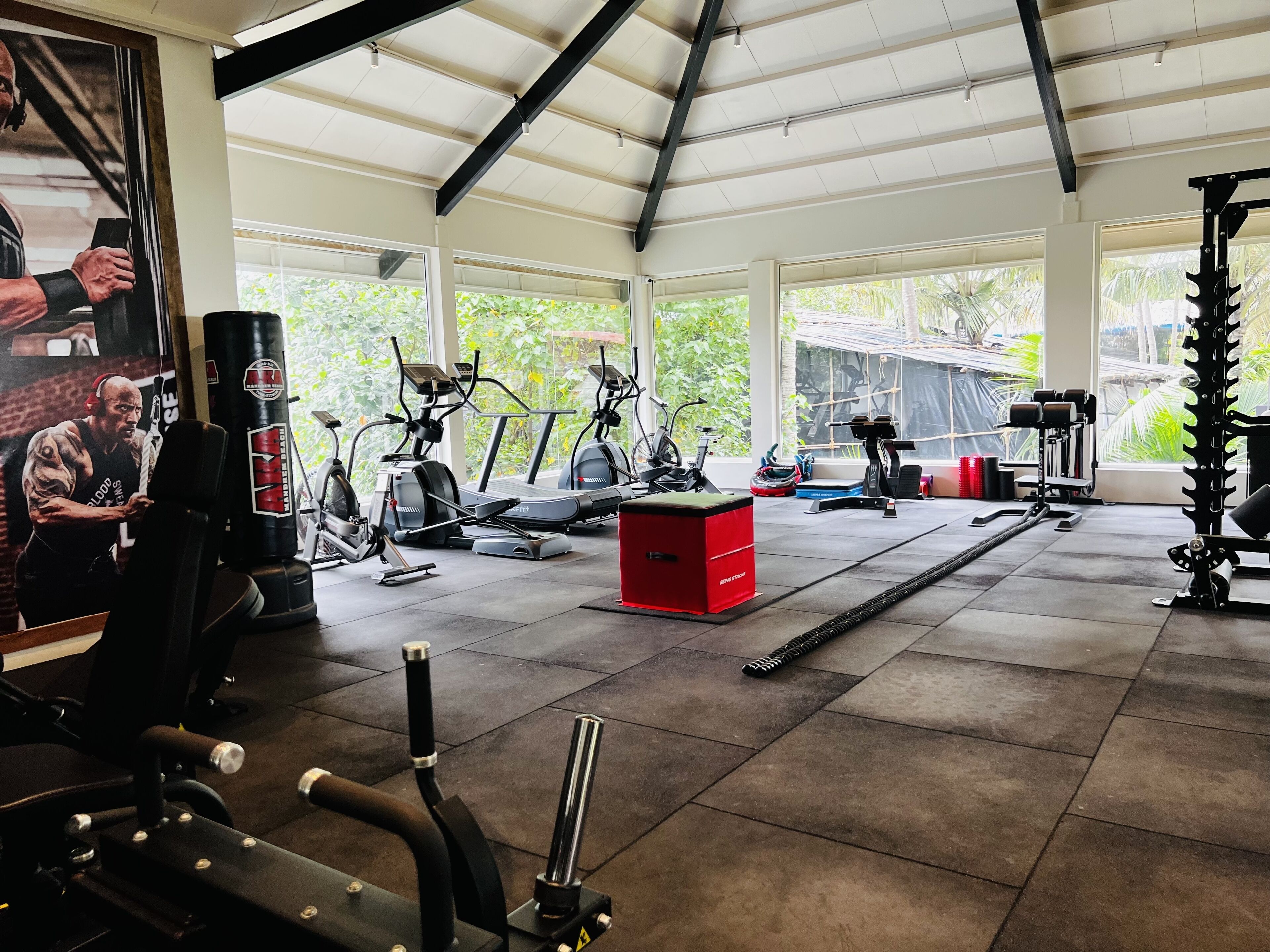 Een sportschool met trainingsapparatuur, grote ramen en een hoge nok.