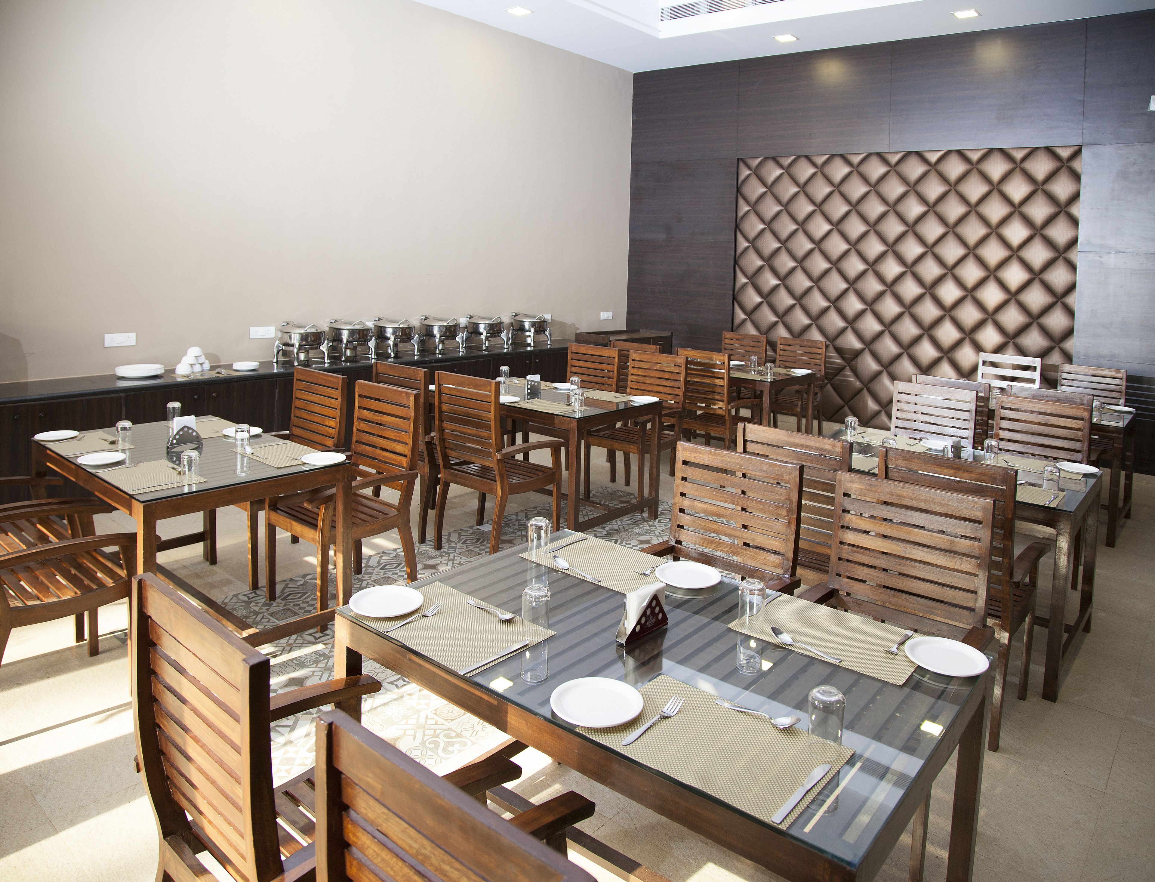A dining area with multiple tables and chairs, buffet setup, and a decorative wall.