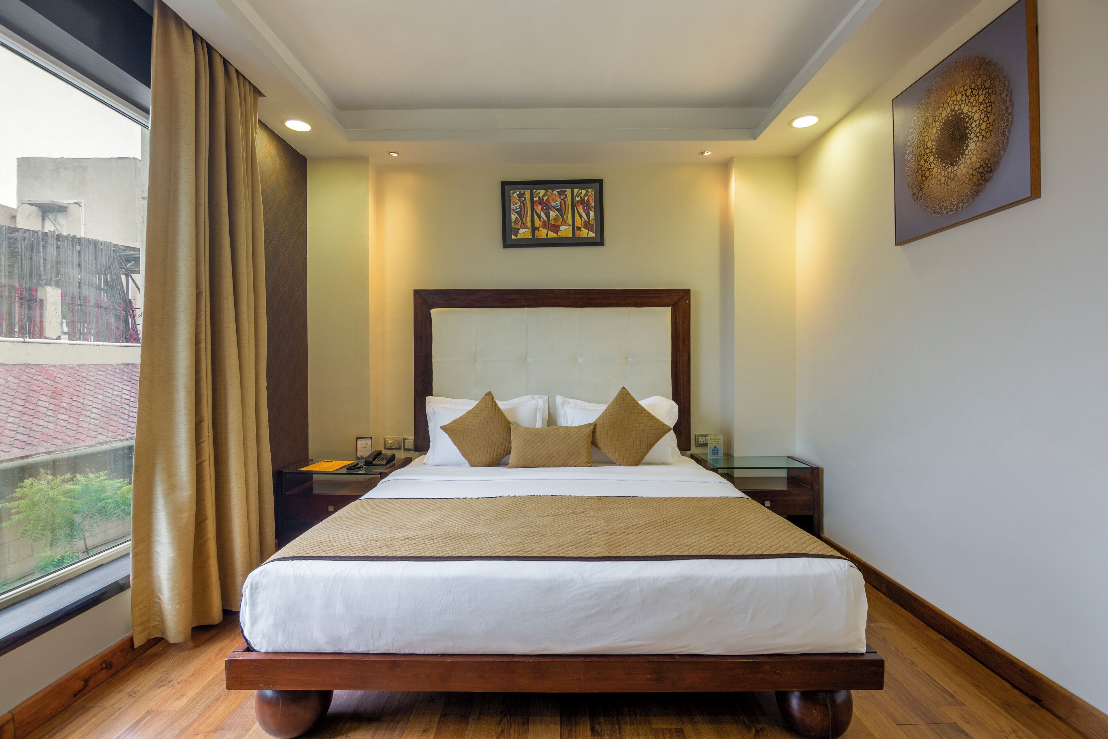 A hotel room with a large bed, a nightstand, a bedside table, and a window with curtains.