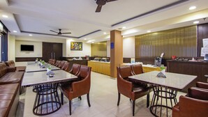 Ein Hotelrestaurant mit mehreren Tischen und Stühlen, einer Rezeption und Deckenventilatoren.
