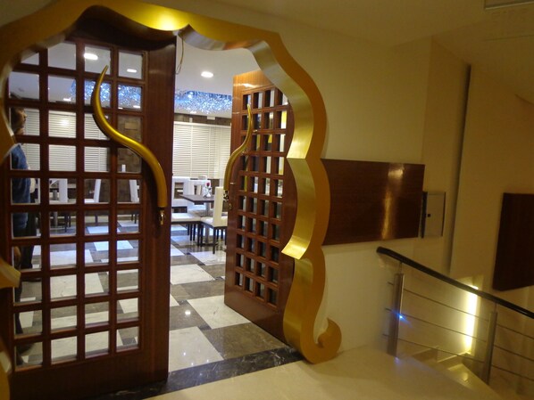 A hotel lobby with a checkered floor, a staircase, and a decorative wooden gate. - Taj Princess The Boutique Hotel (New Delhi)