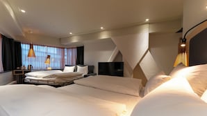 Habitación de hotel con una cama grande, un escritorio, una silla, un televisor y un ventanal con cortinas.