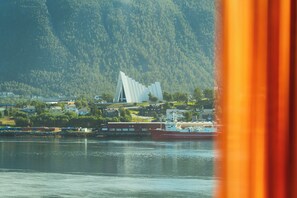 A coastal town with a prominent white building, a body of water, and a mountainous backdrop. - Clarion Hotel The Edge (Tromsø)