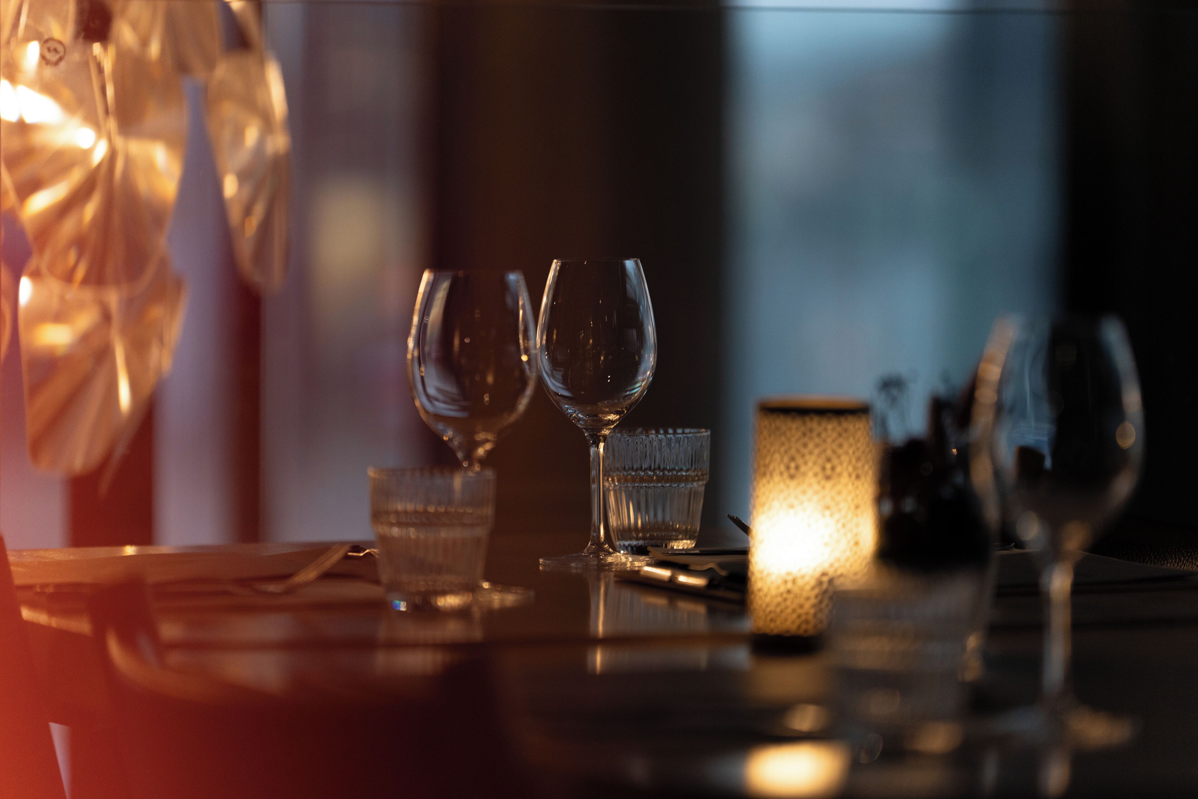 A table with two wine glasses and a candle, suggesting a dining setting.