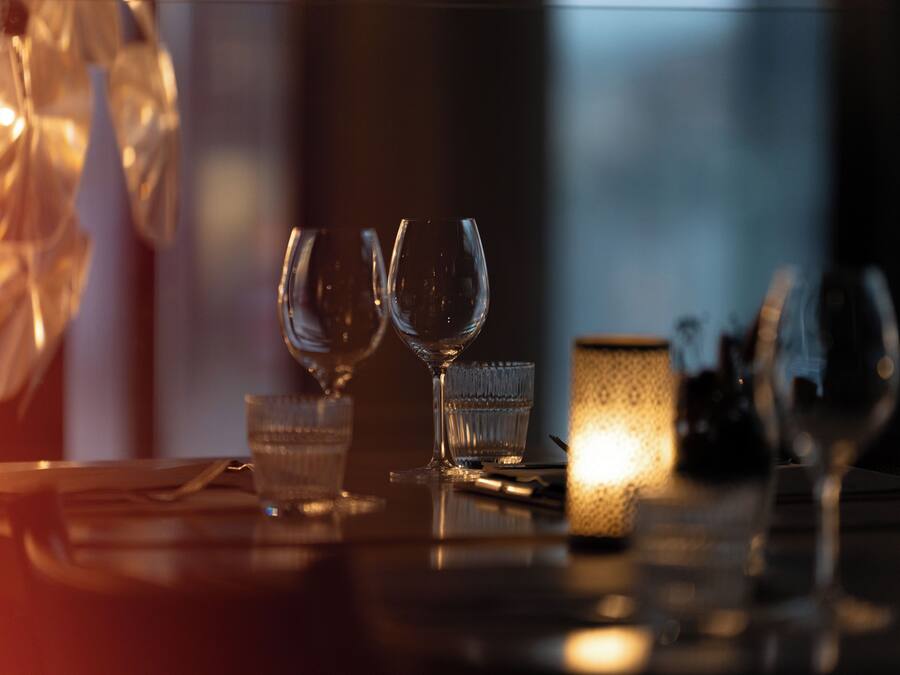 A table with two wine glasses and a candle, suggesting a dining setting.