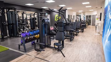 Ein Fitnessstudio mit verschiedenen Trainingsgeräten, darunter Kraftgeräte und Kettlebells.
