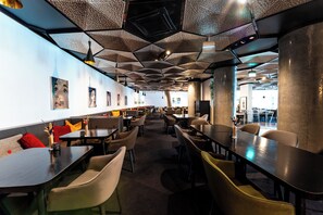 A modern restaurant with hexagonal ceiling panels, multiple seating areas, and artwork on the walls. - Clarion Hotel The Edge (Tromsø)