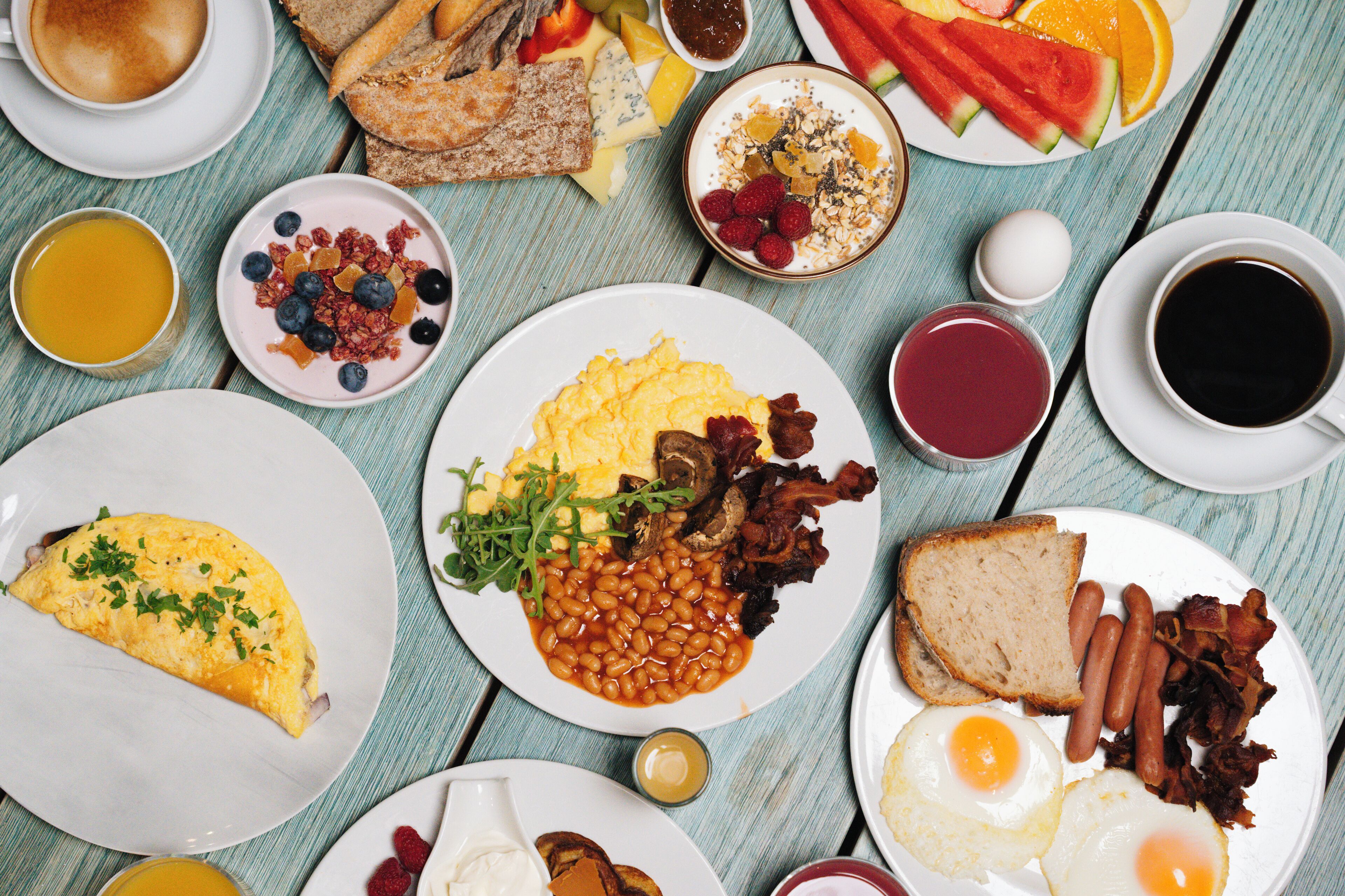 A table with various breakfast items including eggs, bacon, toast, and fruit.