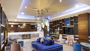 A modern lobby with a blue sofa, wooden shelves, and a TV.