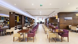 A spacious indoor dining area with multiple tables and chairs, a central aisle, and a wall-mounted television.