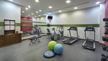 A gym with treadmills, elliptical machines, a bench, and free weights.