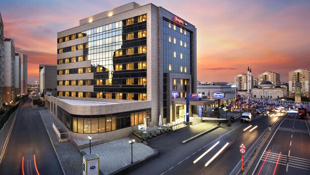 A modern hotel with a glass facade, multiple floors, and a prominent brand sign.