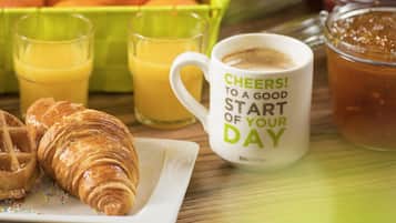 Un desayuno con croissants, zumo de naranja y una taza de café con un mensaje.