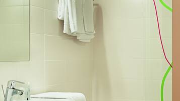 Une salle de bain équipée d’un lavabo, d’un miroir et d’une zone douche.