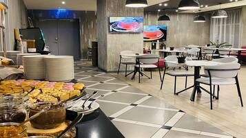 Zona pranzo moderna con servizio a buffet, diversi tavoli e sedie.