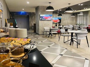 A modern dining area with a buffet setup, multiple tables, and chairs.