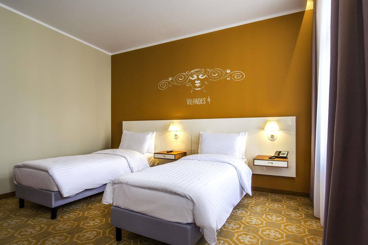 Une chambre d’hôtel avec deux lits, une moquette à motifs et un mur orné d’un décor.