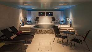 A spa area with a hot tub, lounge chairs, and a small table with candles. - Mercure Riga Centre (Riga)