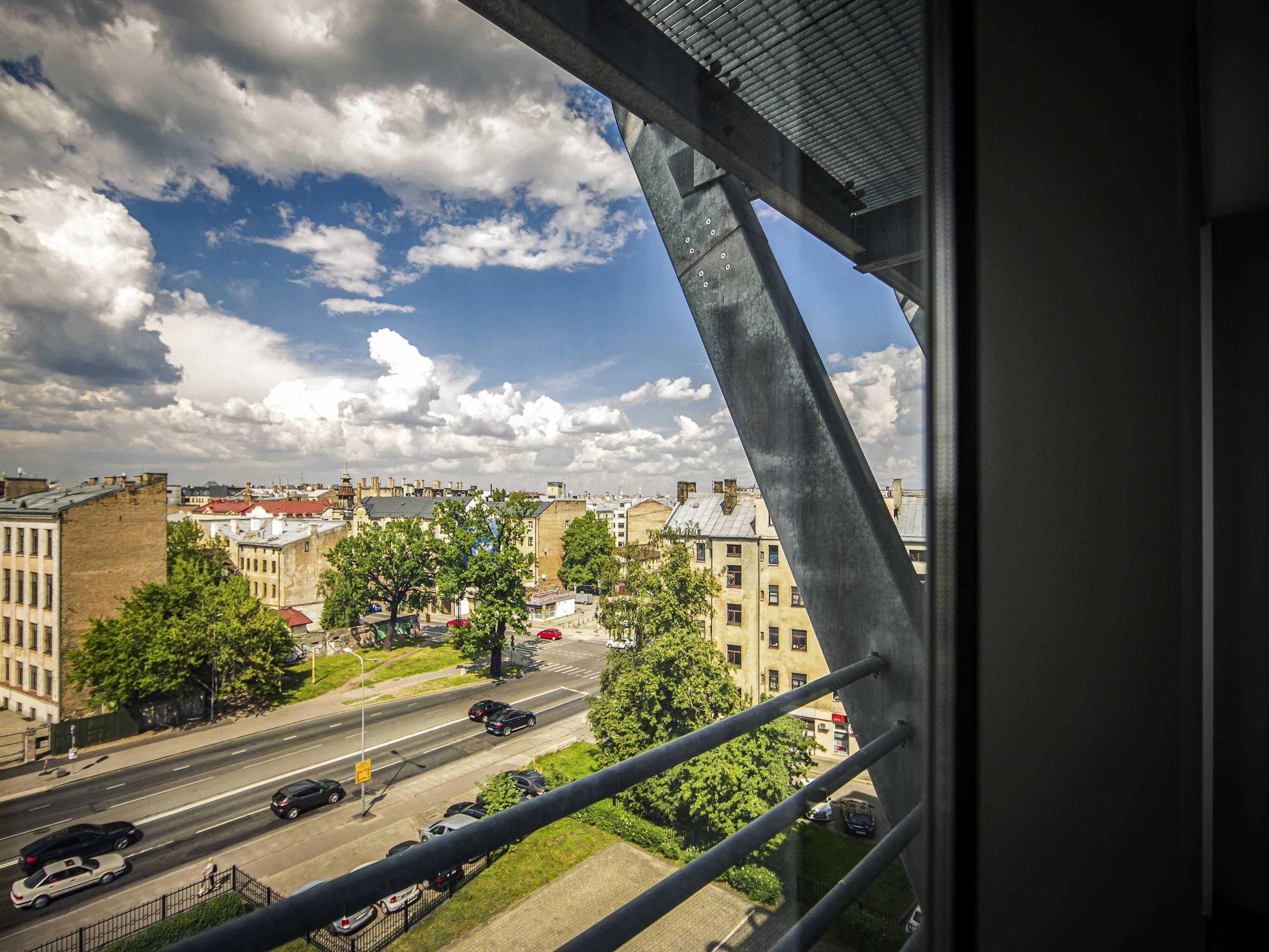 Vista de un paisaje urbano desde un puente, con edificios, árboles y una carretera.