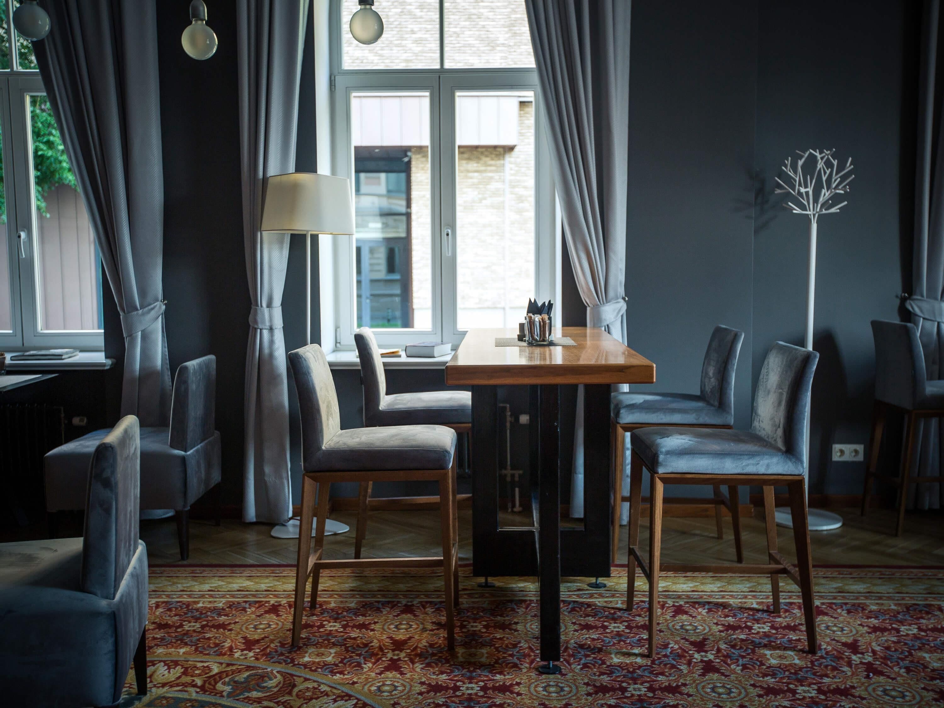 A modern room with a wooden table and four chairs, a floor lamp, and a patterned rug.