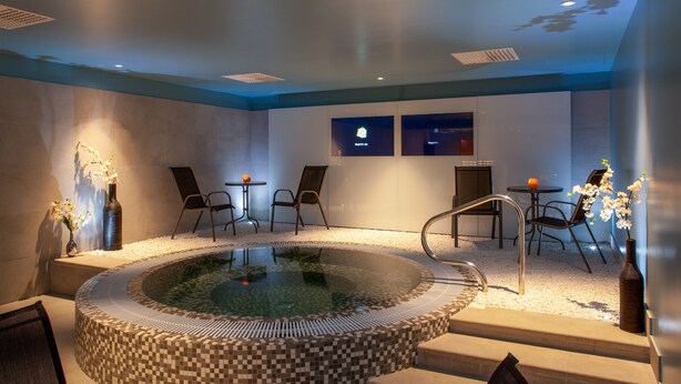 A spa area with a hot tub, seating, and a tiled floor. - Mercure Riga Centre (Riga)
