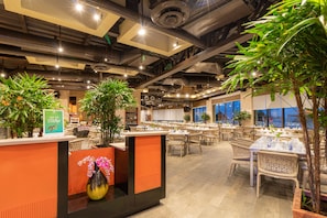 Een restaurant met kamerplanten, gedekte tafels en een modern industrieel plafond.