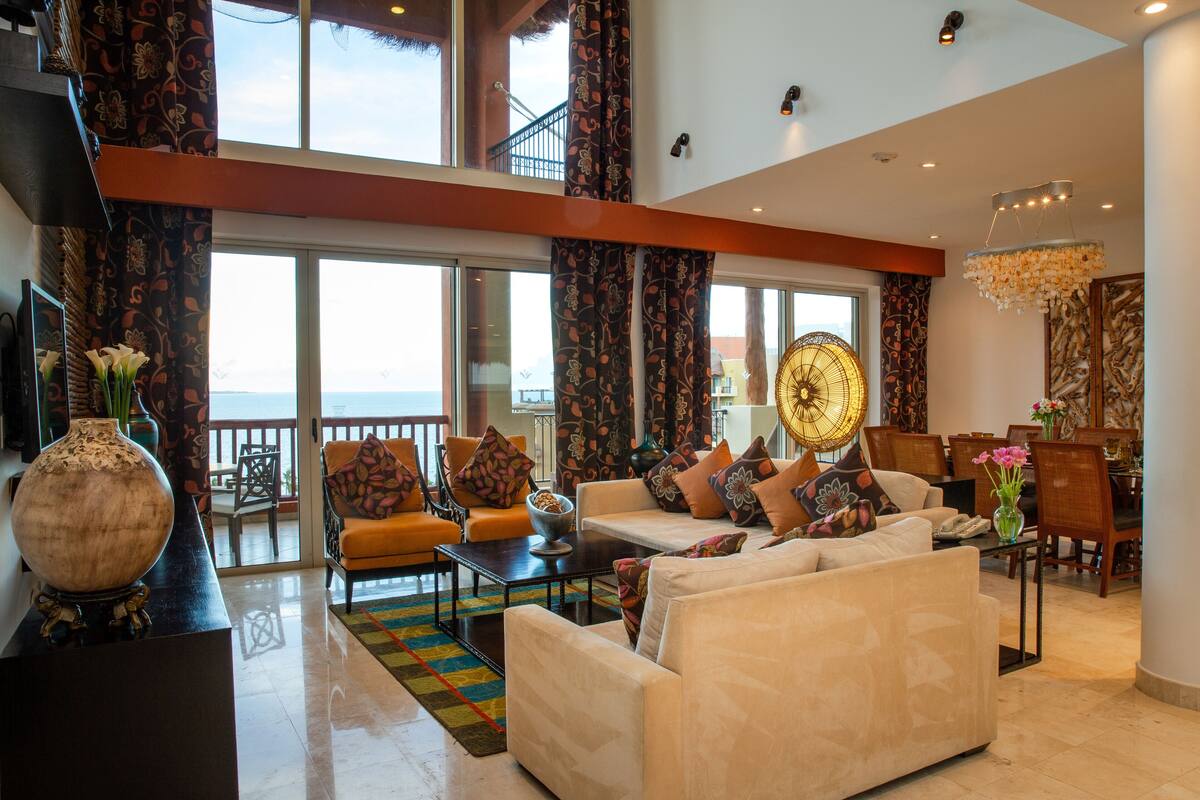 A spacious living room with a large sofa, a coffee table, and a dining area with chairs and a table.