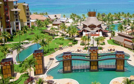 Un resort con varias piscinas, palmeras y una zona de playa.