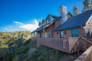 A large, two-story house with a stone chimney, wooden deck, and multiple windows. - Tucker Peak Lodge (Julian)