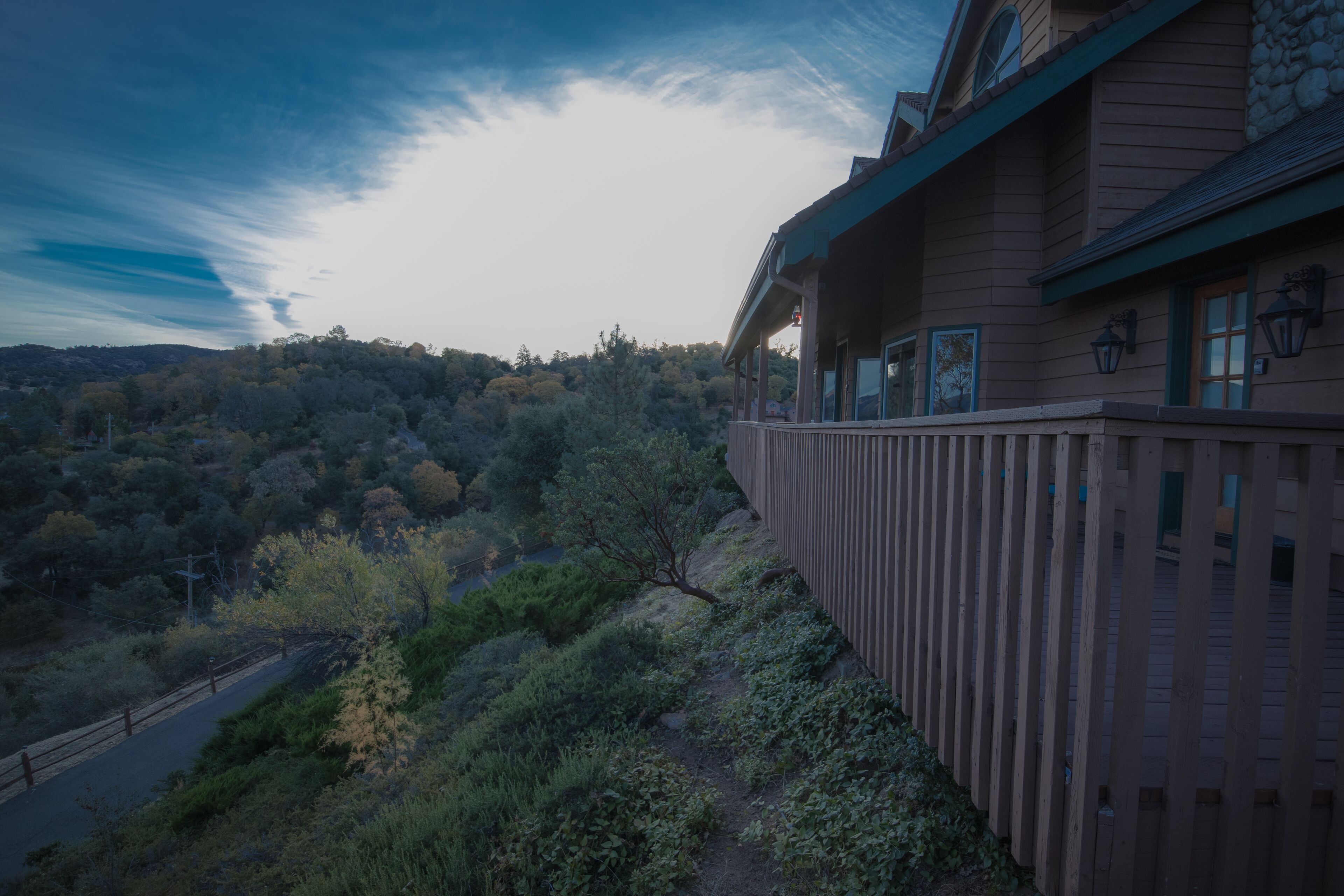 A wooden building with a balcony overlooking a forested hillside.